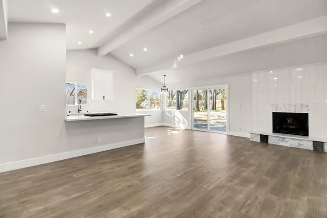 a view of an empty room with a kitchen and a window