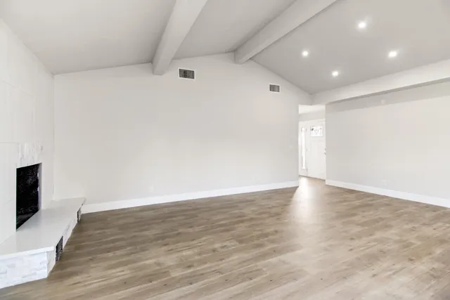 a view of an empty room with wooden floor and a flat screen tv