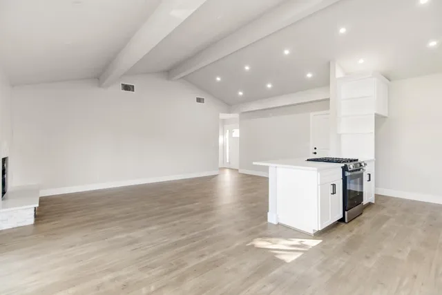 a view of kitchen with stove and white cabinets