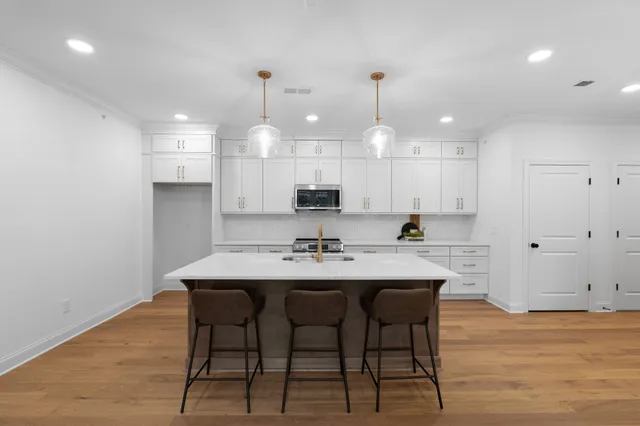 a kitchen with kitchen island a dining table chairs sink and cabinets