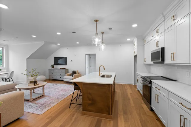 a living room with stainless steel appliances furniture a flat screen tv and kitchen view
