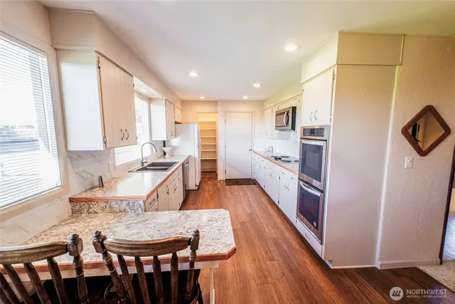 a large kitchen with a table chairs wooden floor and a window