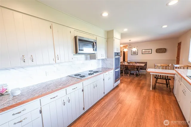 a large kitchen with cabinets wooden floor and stainless steel appliances