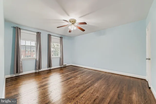 an empty room with wooden floor chandelier fan and windows