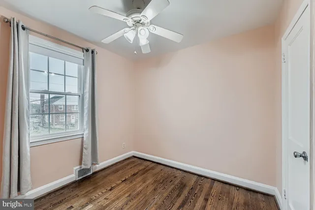 an empty room with wooden floor closet and windows