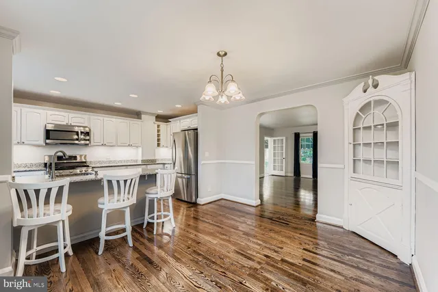 a kitchen with stainless steel appliances a dining table chairs stove and refrigerator
