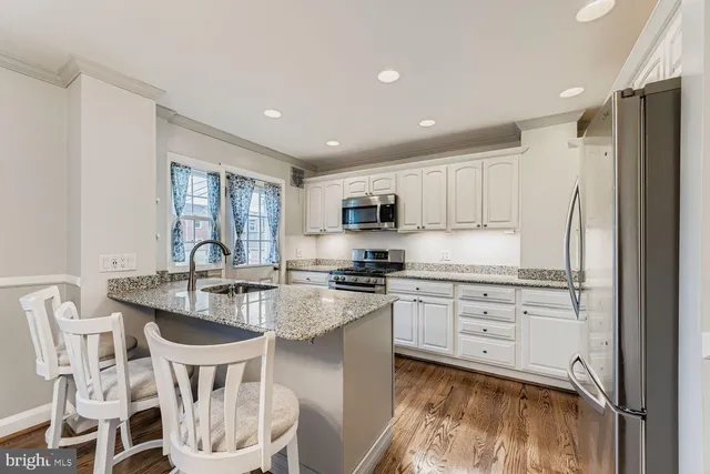 a kitchen with stainless steel appliances granite countertop a stove top oven a sink a dining table and chairs
