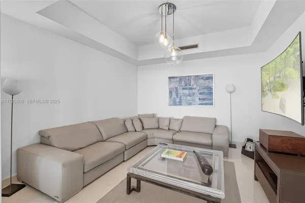 a spacious bedroom with a bed and a flat tv screen on dresser