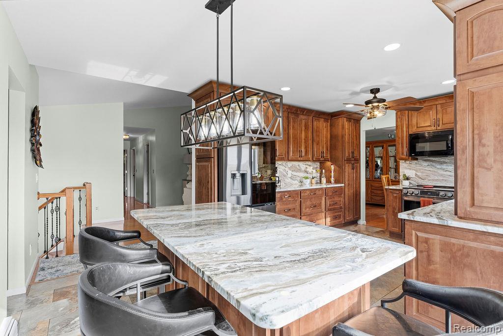 8742 Hyne Road Brighton, MI 48114 - Photo 19 of 65 Kitchen with a breakfast bar area, hanging light fixtures, light stone counters, and wood finish cabinetry