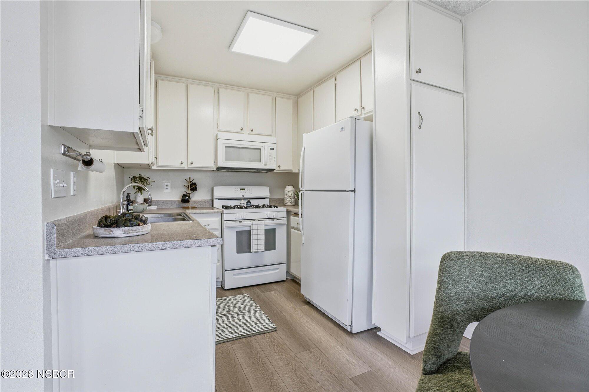 1192 Sumner Place, Unit D Santa Maria, CA 93455 - Photo 6 of 18 a kitchen with white cabinets and white appliances