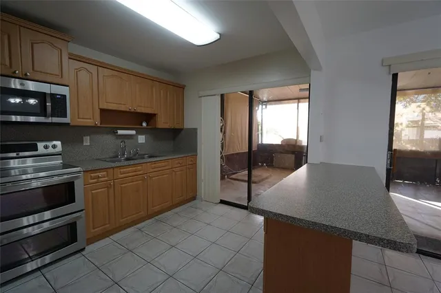 a kitchen with stainless steel appliances granite countertop a stove a sink and a microwave