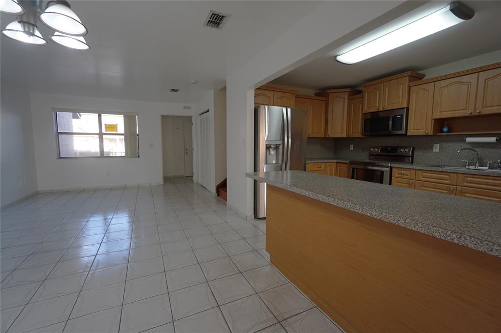 6380 West 24th Court Hialeah, FL 33016 - Photo 7 of 41 a large kitchen with stainless steel appliances a sink a stove a microwave a window and white cabinets