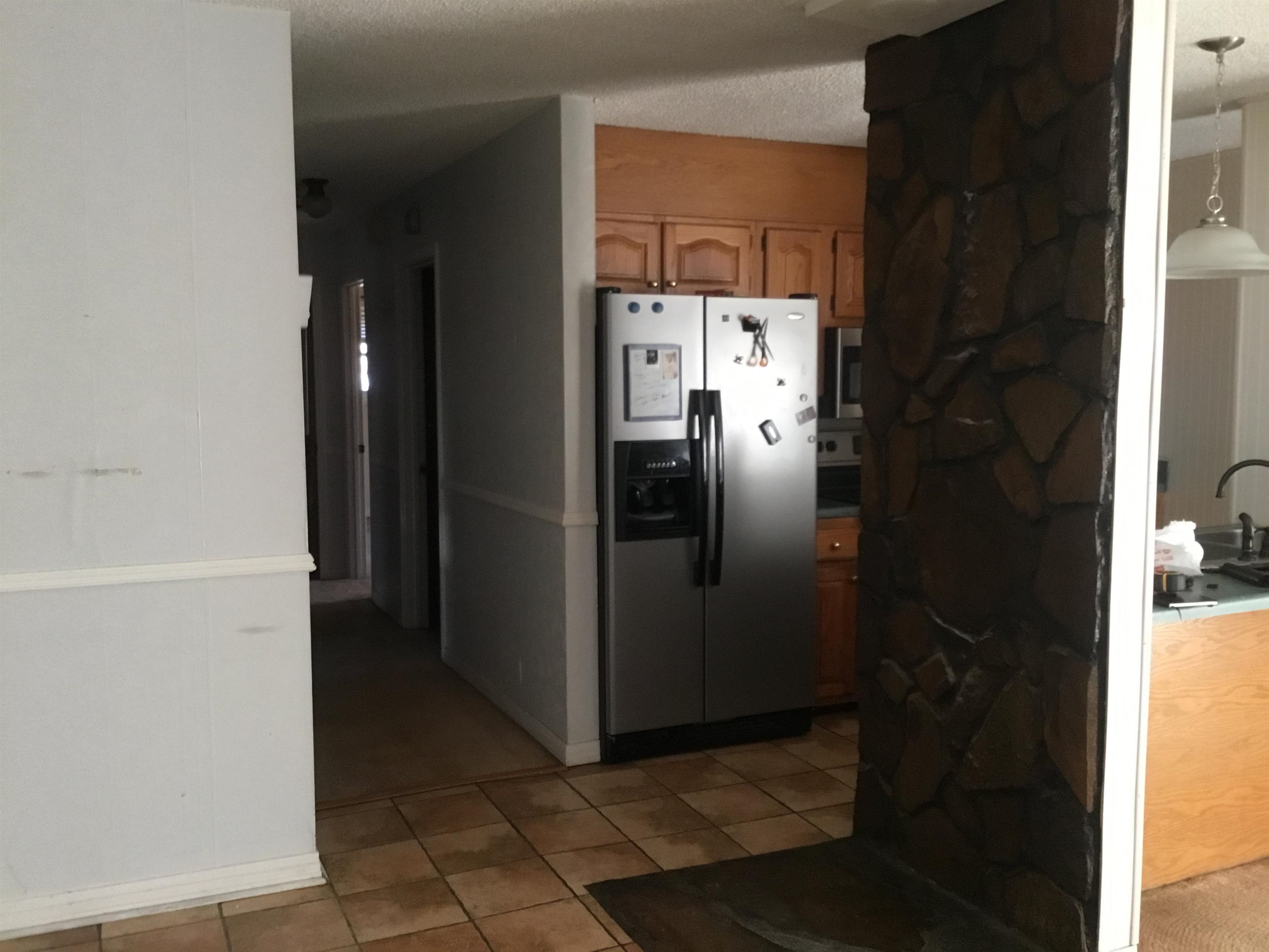 367 Crabtree Road Selmer, TN 38375 - Photo 13 of 23 Kitchen featuring stainless steel appliances, light tile patterned flooring, brown cabinetry, a textured ceiling, and pendant lighting