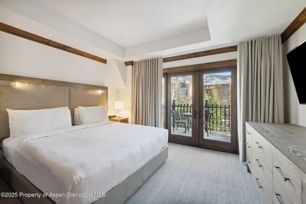 a spacious bedroom with a large bed and a flat tv screen next to a window