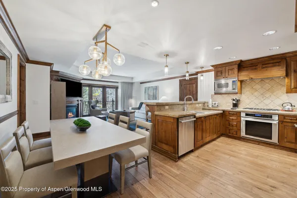 a kitchen with stainless steel appliances granite countertop a stove oven and a dining table with kitchen view