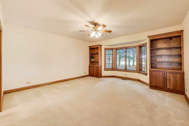 an empty room with chandelier fan and windows