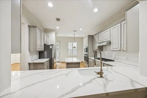 a kitchen with stainless steel appliances kitchen island granite countertop a refrigerator and a sink