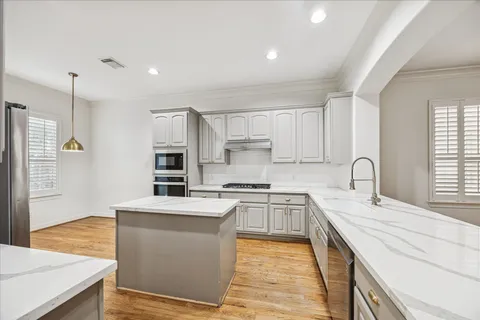 a large kitchen with stainless steel appliances granite countertop a stove a sink dishwasher and a refrigerator with wooden floor