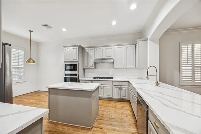 a large kitchen with stainless steel appliances granite countertop a stove a sink dishwasher and a refrigerator with wooden floor