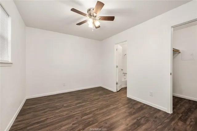 an empty room with wooden floor and ceiling fan