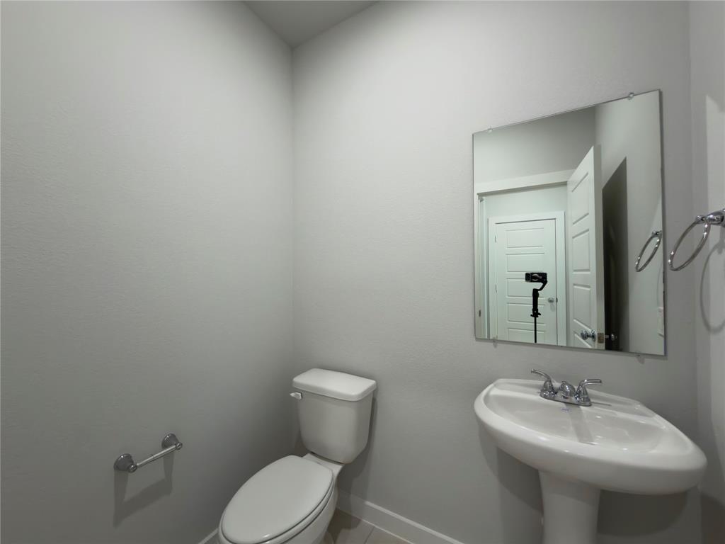 120 Millwood Road Lavon, TX 75166 - Photo 17 of 34 Pedestal sink with chrome faucet, toilet, and wall-mounted mirror