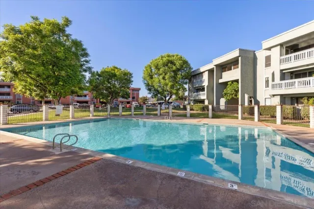 a view of a swimming pool with a bench and trees in the background