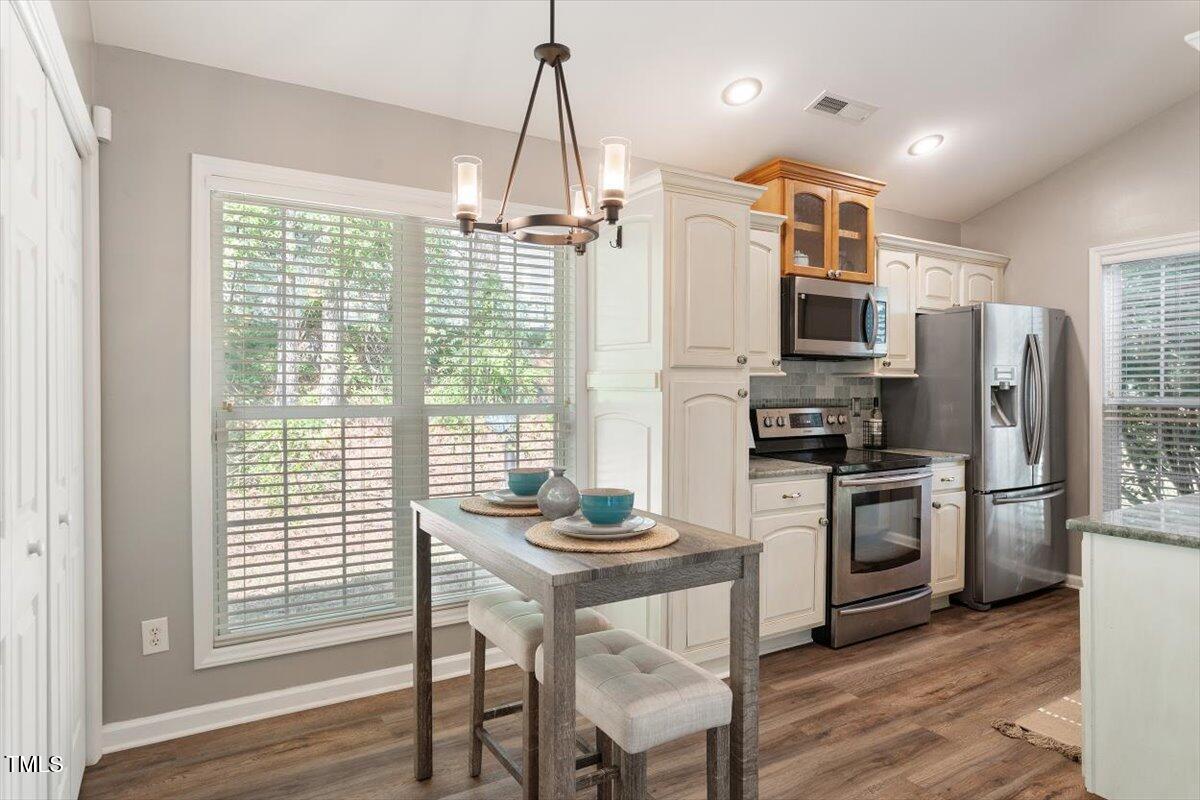 6412 Forest Ridge Drive Durham, NC 27713 - Photo 18 of 32 a kitchen with stainless steel appliances granite countertop a refrigerator a stove a sink dishwasher a dining table and chairs with wooden floor