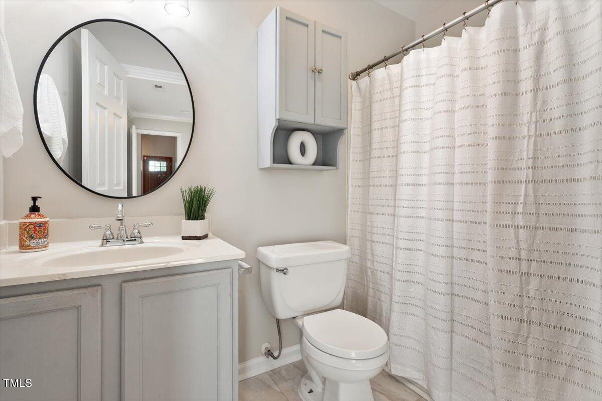 6412 Forest Ridge Drive Durham, NC 27713 - Photo 27 of 32 a bathroom with a toilet sink vanity and mirror