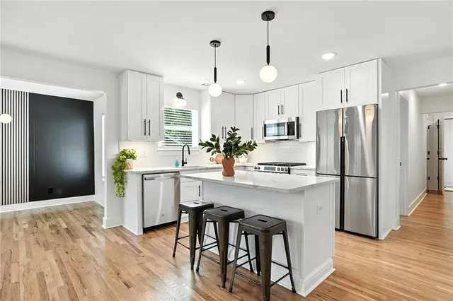 a kitchen with kitchen island granite countertop a refrigerator a stove a sink and white cabinets with wooden floor