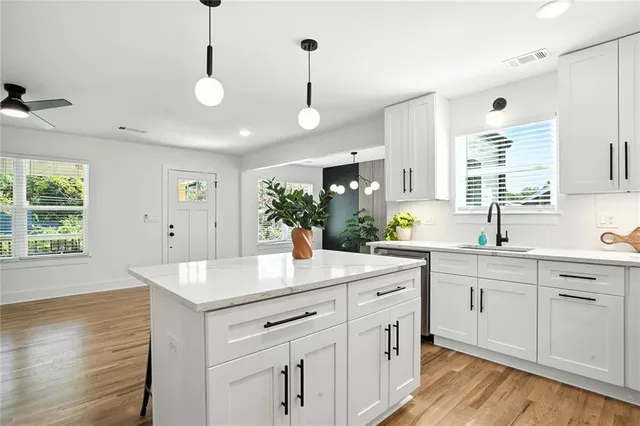 a kitchen with a sink dishwasher and white cabinets with wooden floor