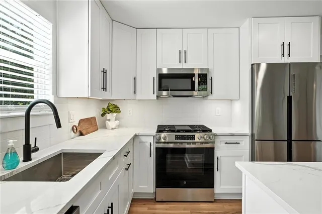 a kitchen with appliances a sink cabinets and a window