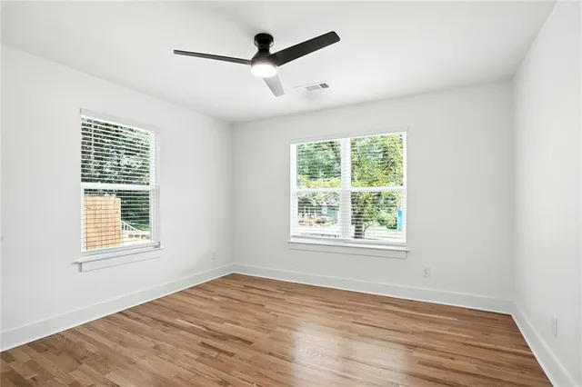 an empty room with wooden floor and windows