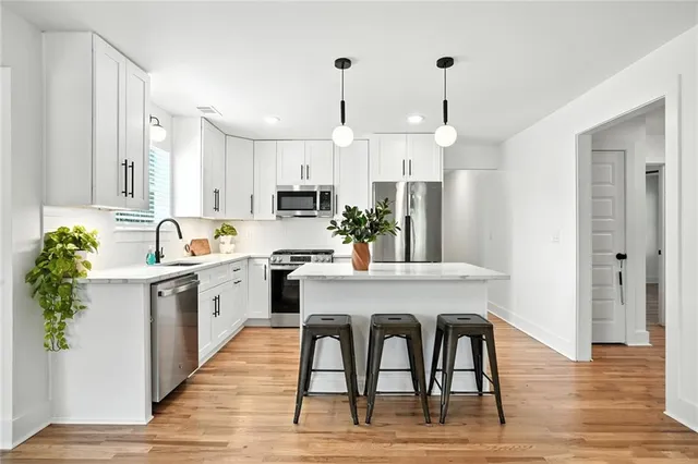 a kitchen with stainless steel appliances granite countertop a white refrigerator a sink dishwasher a dining table and chairs with wooden floor