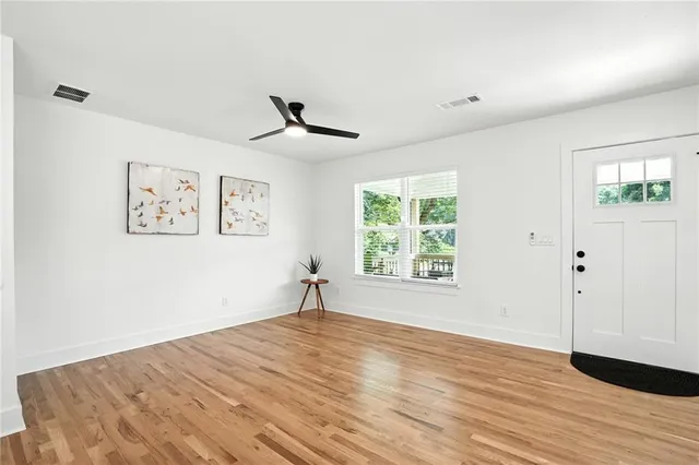 a view of an empty room with wooden floor and a window