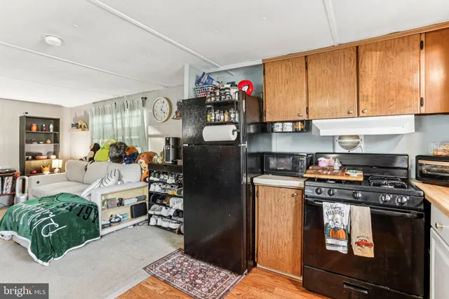 a living room with furniture a flat screen tv and a refrigerator