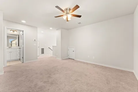 an empty room with chandelier fan and windows