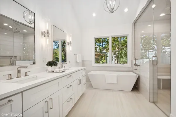 a spacious bathroom with a double vanity sink a large mirror and shower