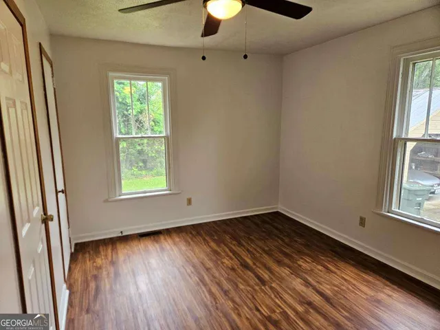 an empty room with wooden floor and windows