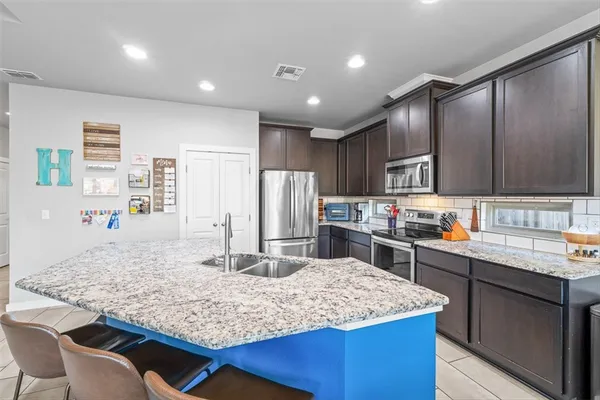 a kitchen with kitchen island granite countertop a sink stove and refrigerator
