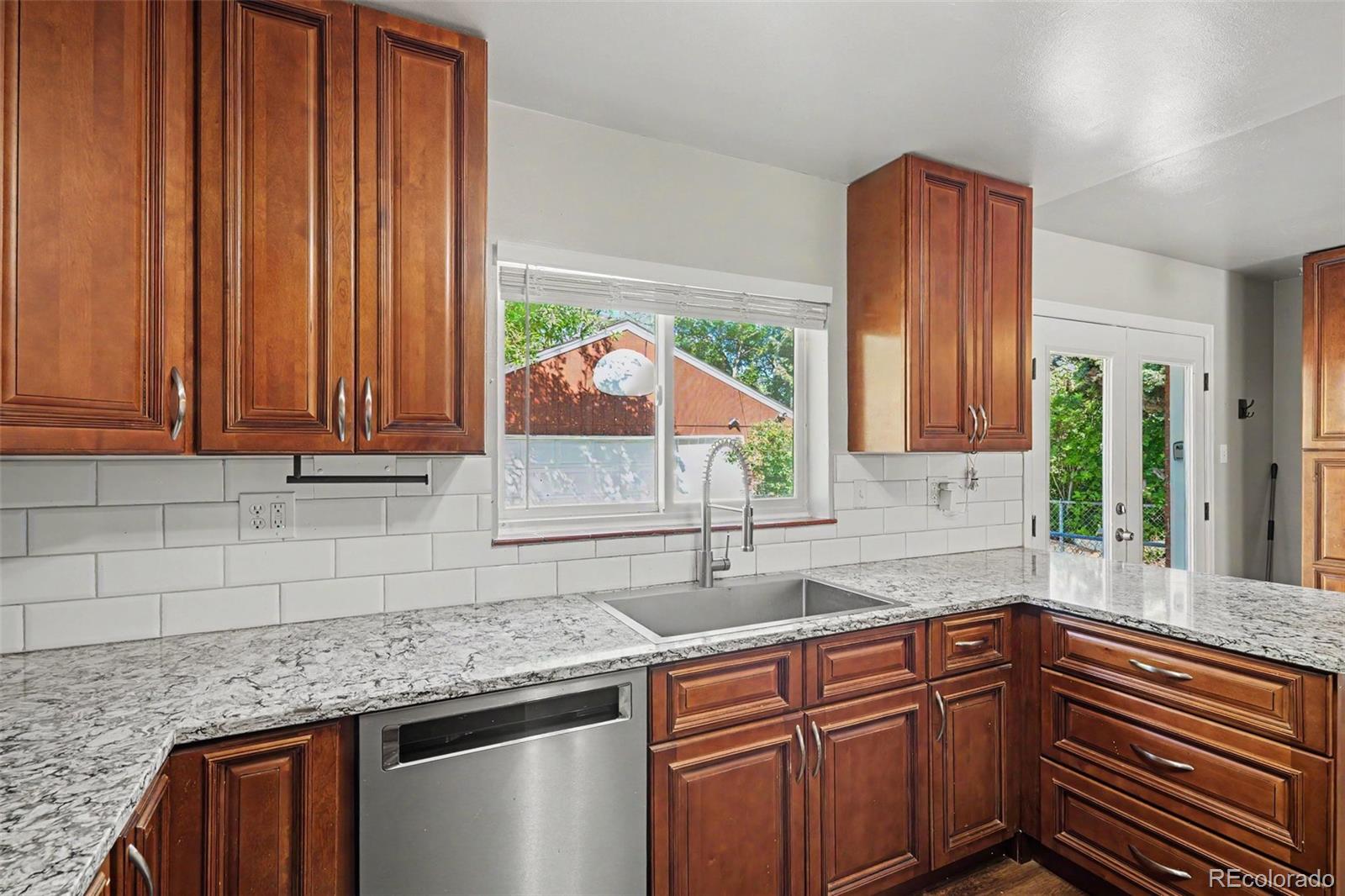 3217 South Stuart Street Denver, CO 80236 - Photo 10 of 29 a kitchen with stainless steel appliances wooden cabinets a sink and a large window