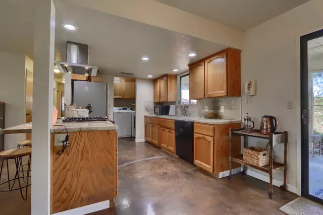 a large kitchen with stainless steel appliances kitchen island granite countertop a refrigerator and a stove top oven