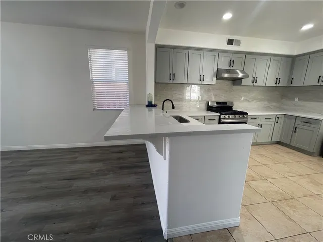 a kitchen with kitchen island granite countertop a sink stove and cabinets