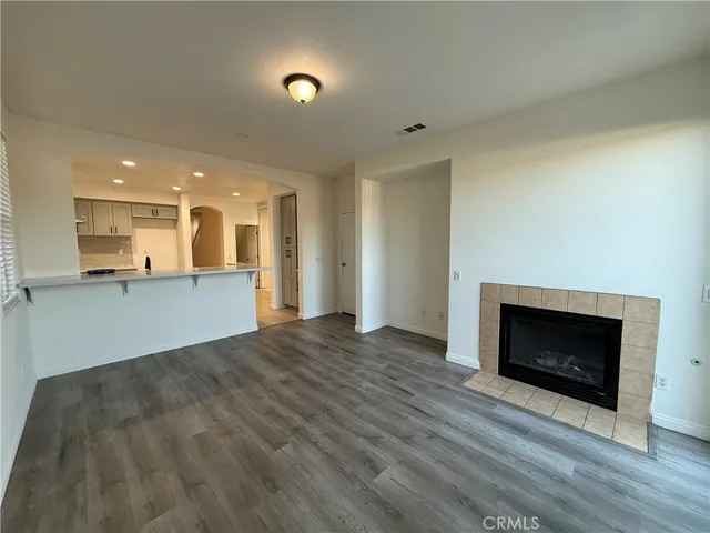 a view of a living room a kitchen with a fireplace and wooden floor