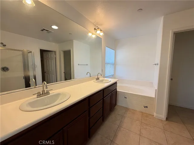 a bathroom with a sink double vanity granite tub shower and a mirror