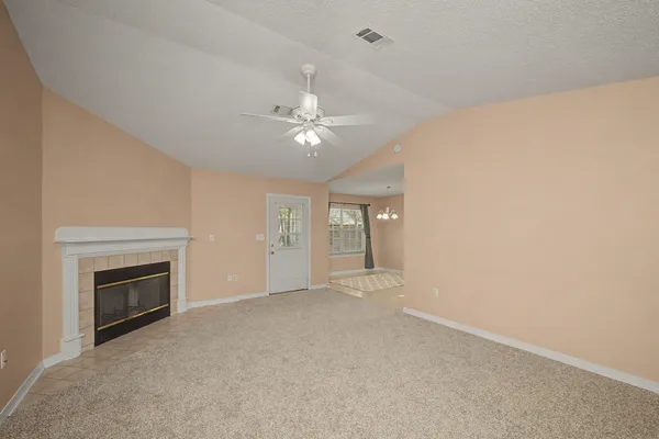 an empty room with chandelier fan and fireplace