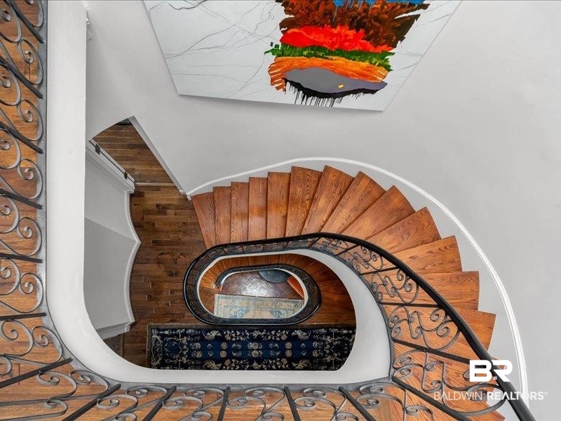 109 Eaton Square Mobile, AL 36608 - Photo 19 of 26 Hardwood spiral staircase featuring a wrought iron banister, white risers, and a central newel post