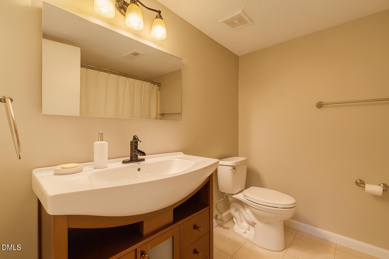 677 Pine Ridge Place, Unit 677 Raleigh, NC 27609 - Photo 4 of 9 a bathroom with a sink a toilet and mirror