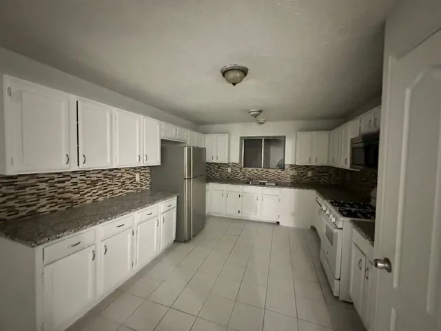 a large white kitchen with a stove top oven