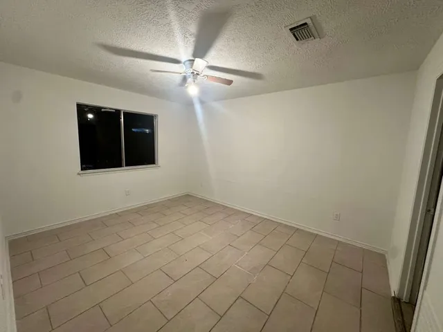 an empty room with windows and fan