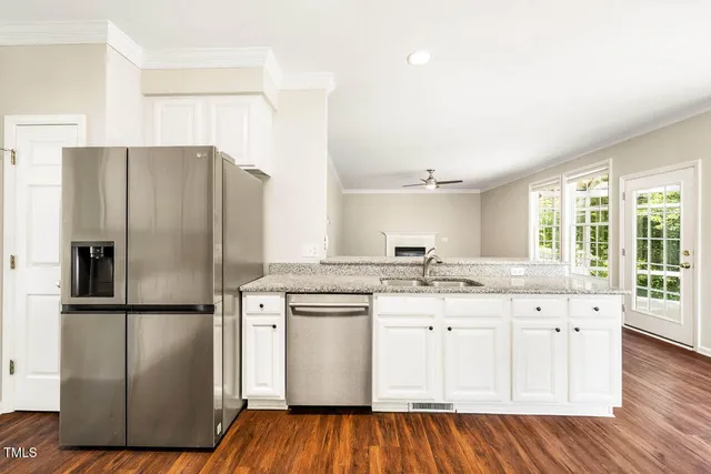 a kitchen with stainless steel appliances granite countertop a refrigerator a sink dishwasher a stove and white countertops with wooden floor